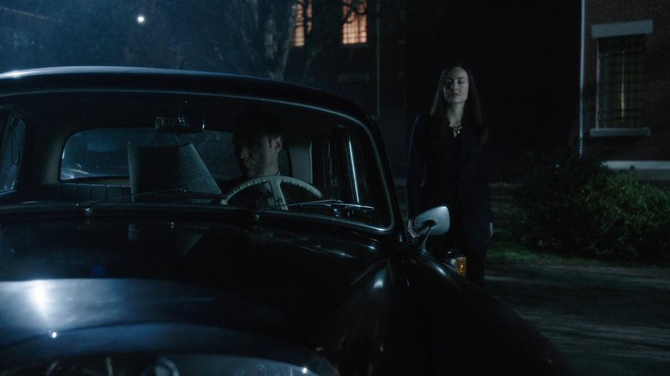 Nora walks up to a man sitting in his car.