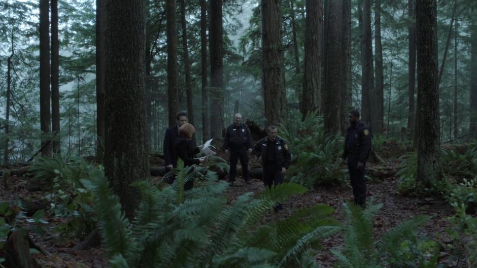 Scully and Mulder review the report while the Chief briefs them on the crime scene with officers Sean and Wentworth