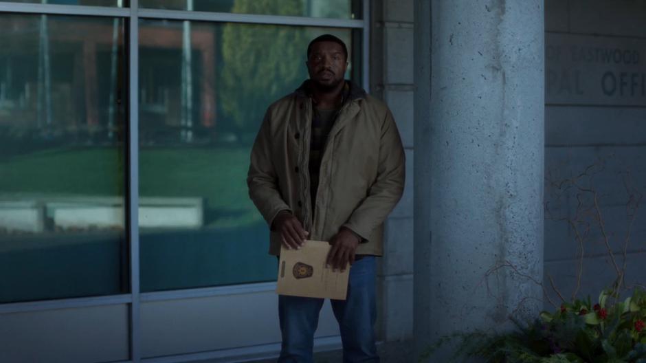 Officer Wentworth stands in the shadows with his folder of evidence.