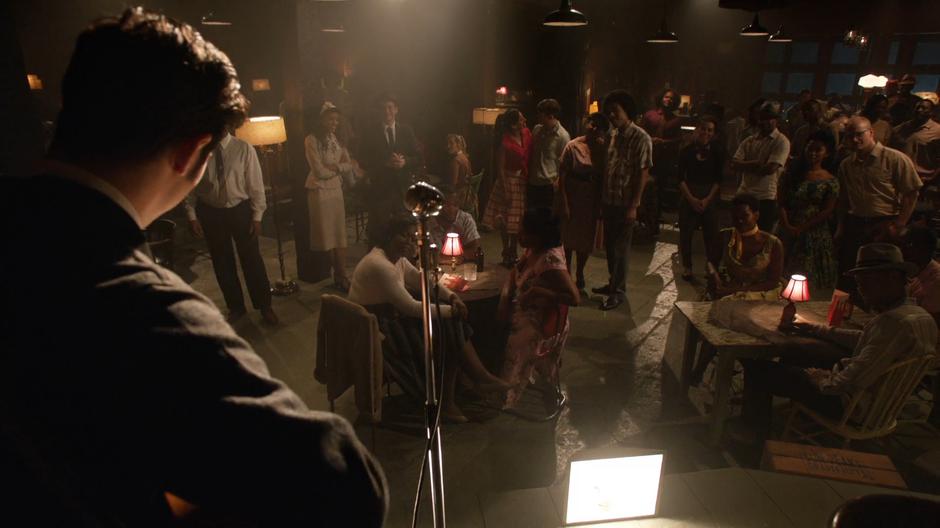 Elvis prepares to play in front of the bar while Amaya and Nate talk.