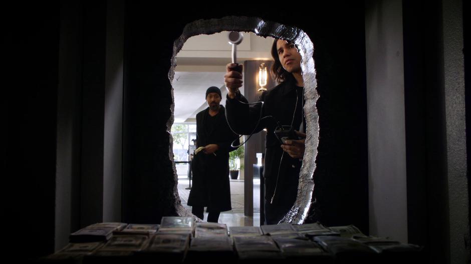 Joe watches as Cisco examines the melted hole in the vault door.