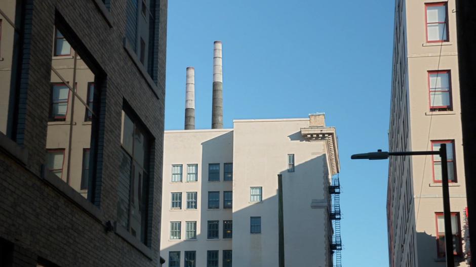 Two smokestacks sit atop a building near the alley.