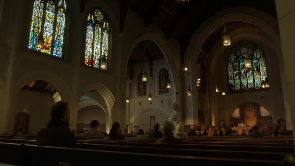 A congregation sits in church listening to a priest.