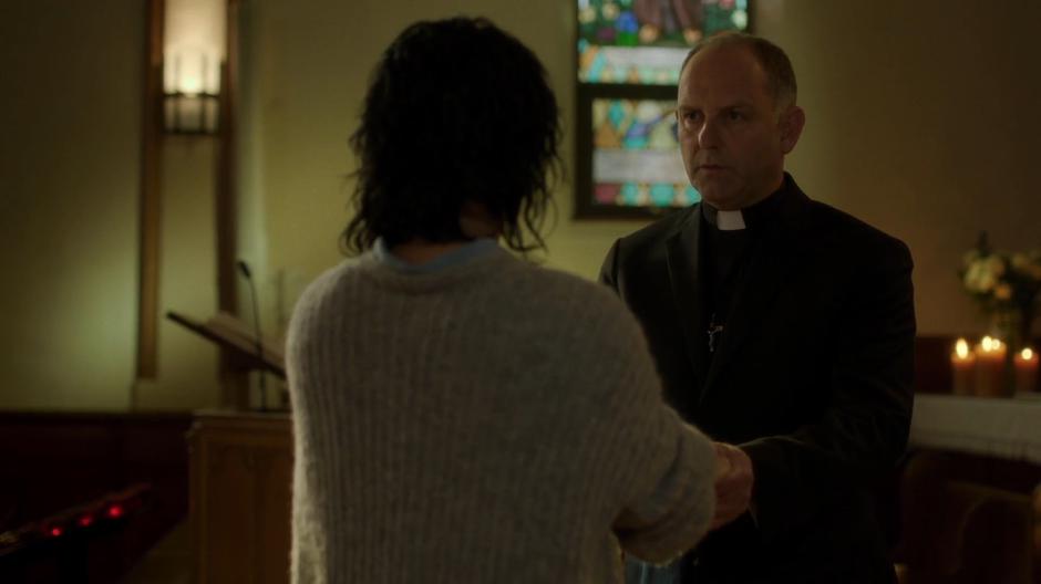 Father Hardy holds Juliet Bocanegra's hands while she prays with him.