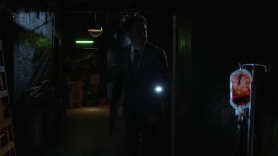 Mulder walks down into the dark basement where he finds medical supplies.