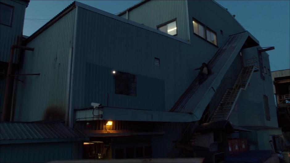 William slides down the roof over the outdoor stairs of the building.