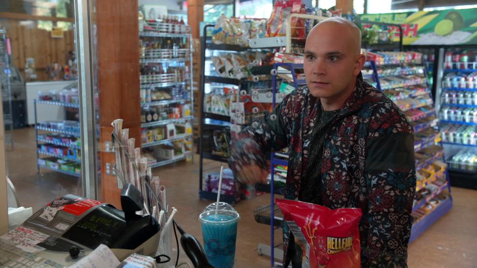 Don E knocks on the protective glass when the cashier start to put his booze back.