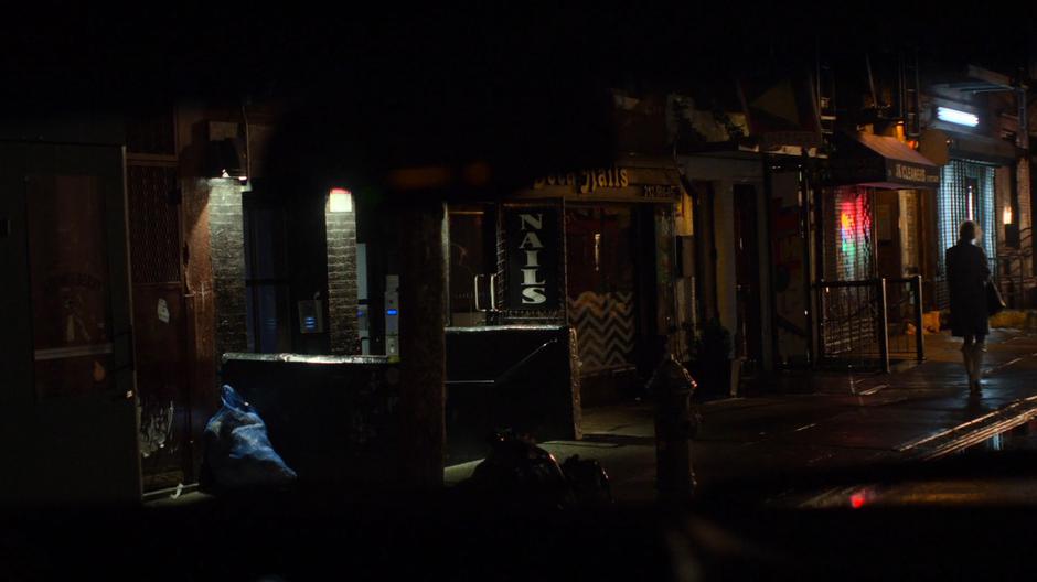 Trish is visible through the windshield of the mysterious SUV as she approaches a building.