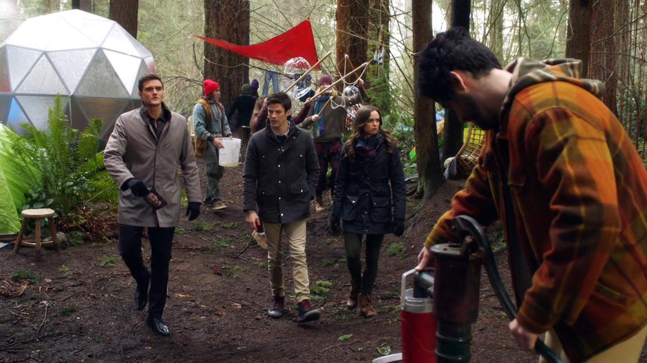 Ralph, Barry, and Caitlin walk through the camp asking about Edwin Gauss.