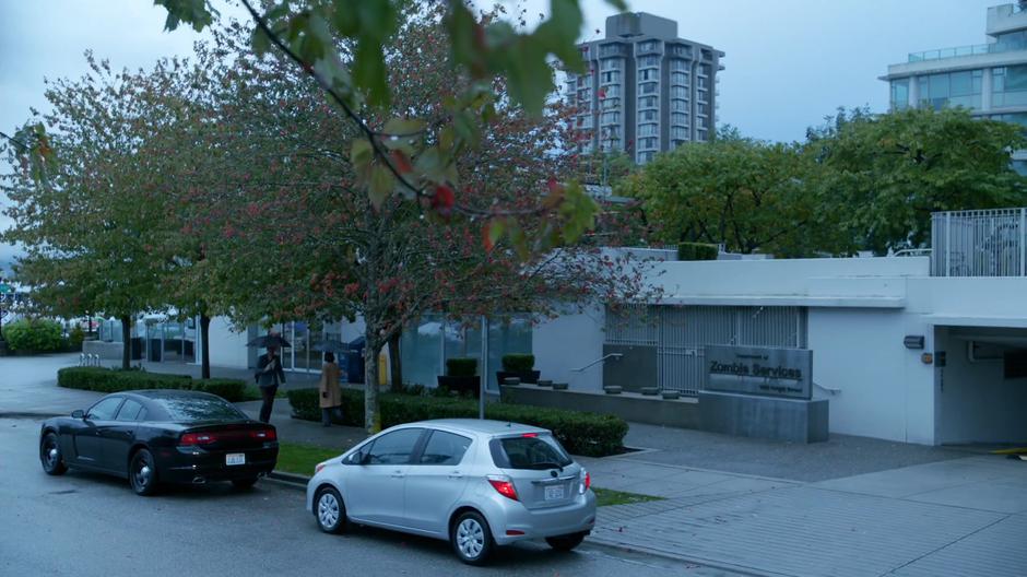 Liv pulls her car up behind Clive's in front of the Zombie Services office.