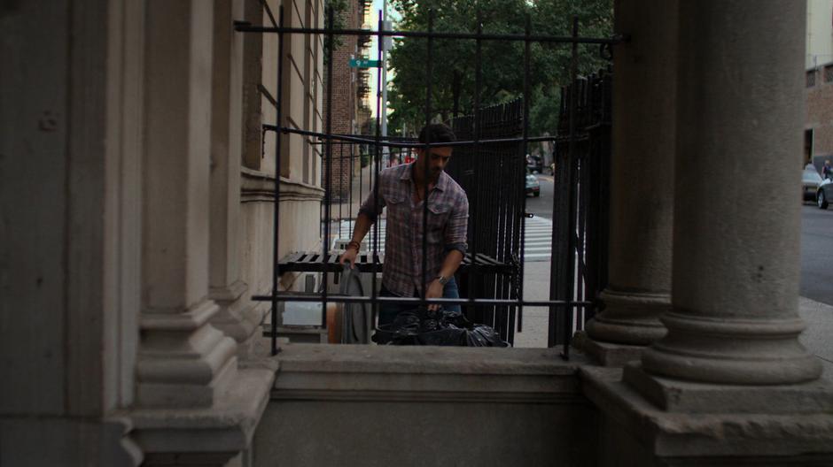 Oscar puts trash into the cans out front of the apartment building.