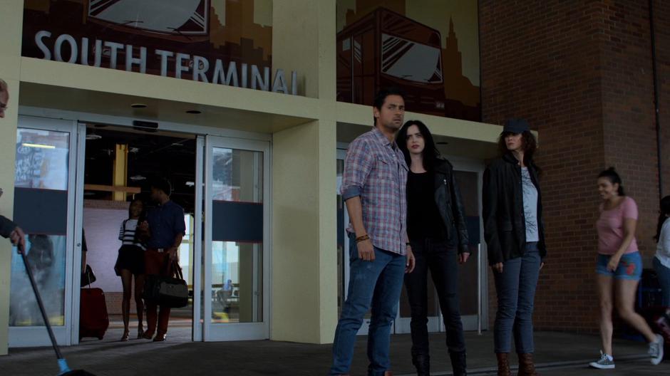 Oscar, Jessica, and Alisa look around outside the terminal for the bus.