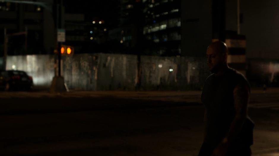 A guy walks down the sidewalk to the bus stop.