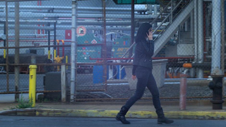 Jessica talks on the phone while walking past the jail's fence.