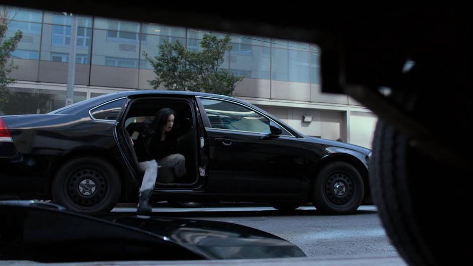 Jessica kicks off the back door of the car and climbs out.