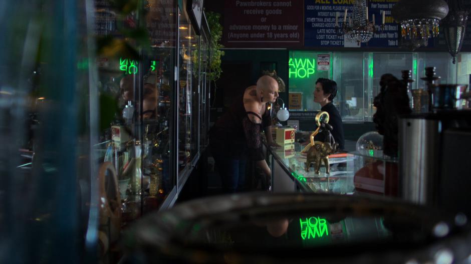 The employee reaches beneath the counter for Hogarth's stuff.