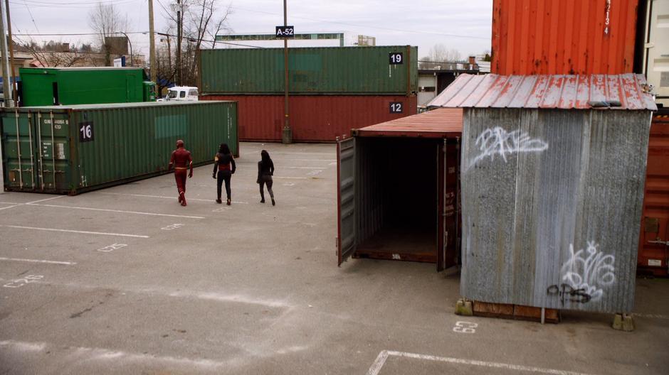 Barry, Cisco, and Cynthia walk towards container 16.