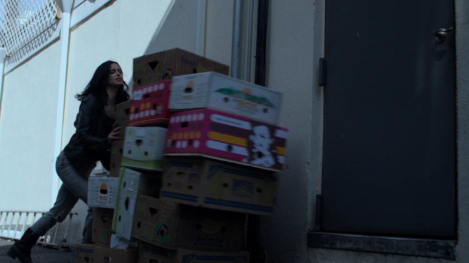 Jessica pushes a pile of boxes in front of the back door to slow down pursuit.