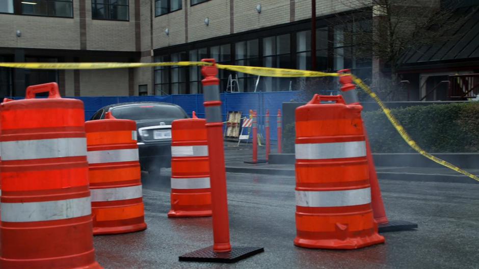 The cultist's car crashes through a construction barrier to the building.