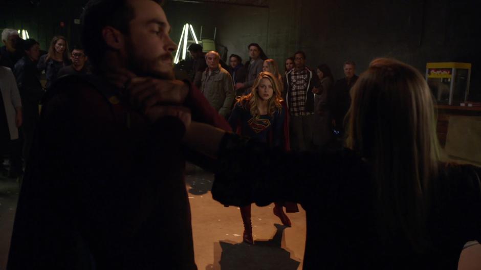 Supergirl lands in the middle of the room as Olivia uses her new powers to strangle some dude.