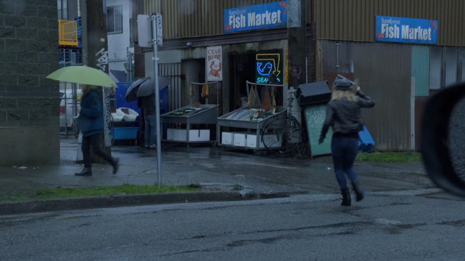 Liv holds a newspaper over her head to keep the rain off while running across the street to the fish market.