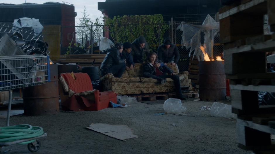 Mace Diller and a few other humans watch the video of the sermon while sitting in a couch in an empty lot.