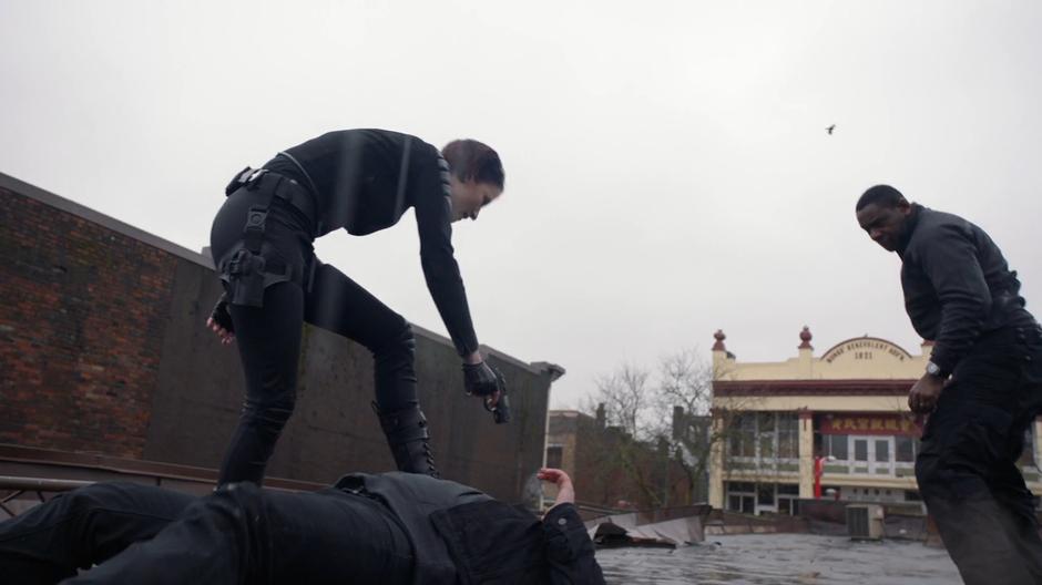 J'onn lands on the roof next to where Alex is holding the killer at gunpoint.