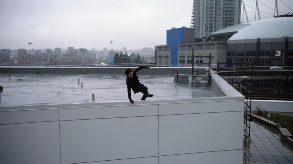 Alex leaps over the edge of the upper roof.