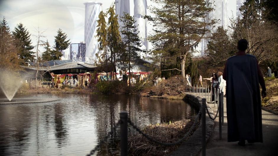 People walks around a pond in the middle of the park.