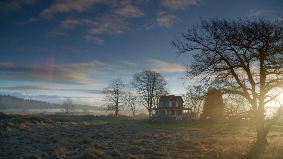 Establishing shot of the safe house surrounded by fog just after sunrise.