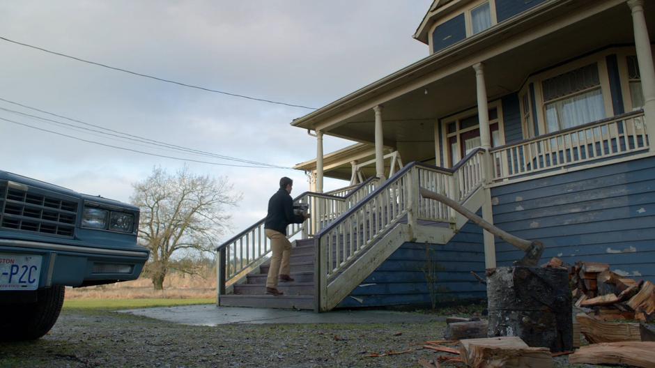 Major walks up the steps of the house with an armful of firewood.