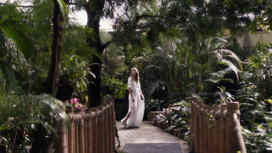 Kara looks around inside the dome while wearing a swooshy white dress.