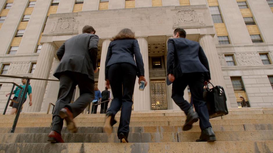 Bull, Captain Mathison, and Benny walk up the steps to the courthouse.