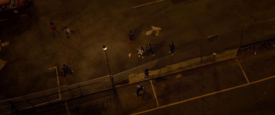 The kids play basketball in the lot far below the apartment.