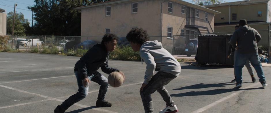 Several young kids play basketball in the lot in the present day.