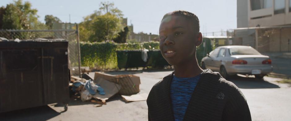 One of the young boys playing basketball watches as his friends run over to the Wakandan vessel.