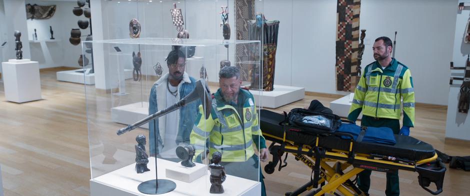 Killmonger and Ulysses Klaue examine the Wakandan artifact in the display case.