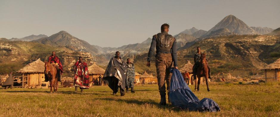 W'Kabi and several of his guards approach Killmonger who is dragging Ulysses Klaue's body wrapped in a tarp.