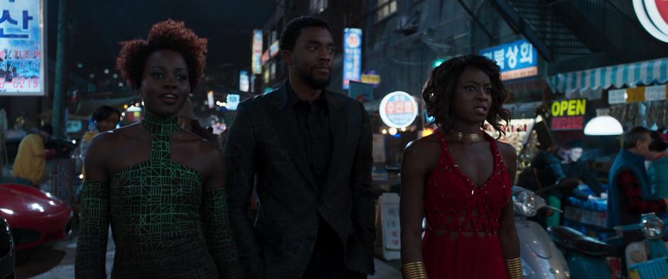 Nakia, T'Challa, and Okoye walk through the market.