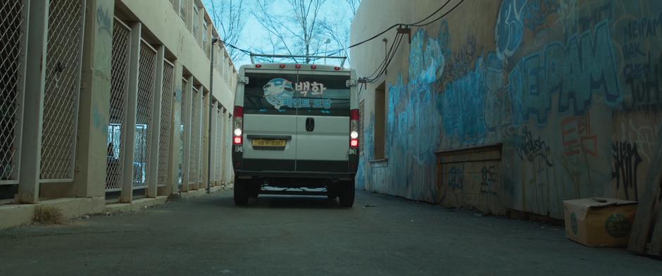 The suspicious van backs into the alley behind the building.