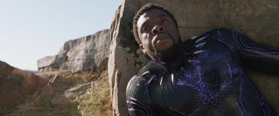 T'Challa leans against a rock in the middle of the battle.