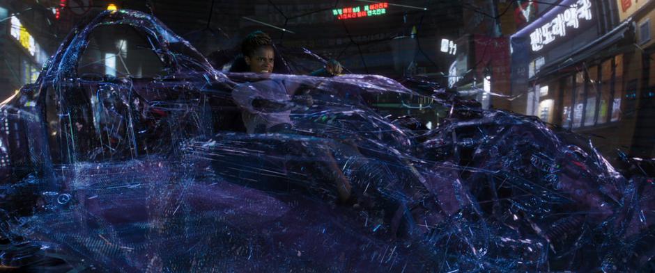 Shuri braces as her driving hologram turns off as the car she was driving is destroyed.