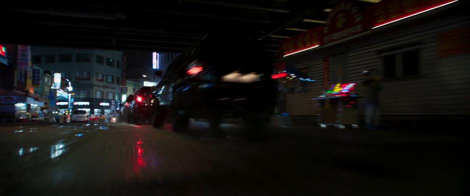 Ulysses Klaue's convoy of SUVs speed down the street under a bridge.