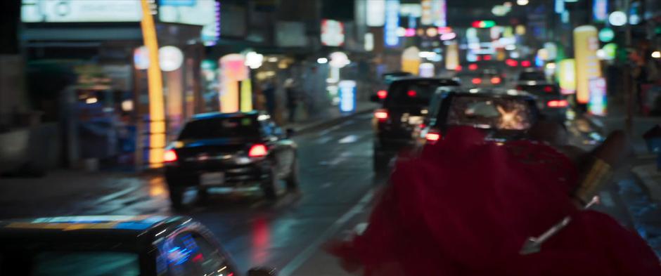 Okoye clings to the top of the car as one of the goons fires at her from the SUV.