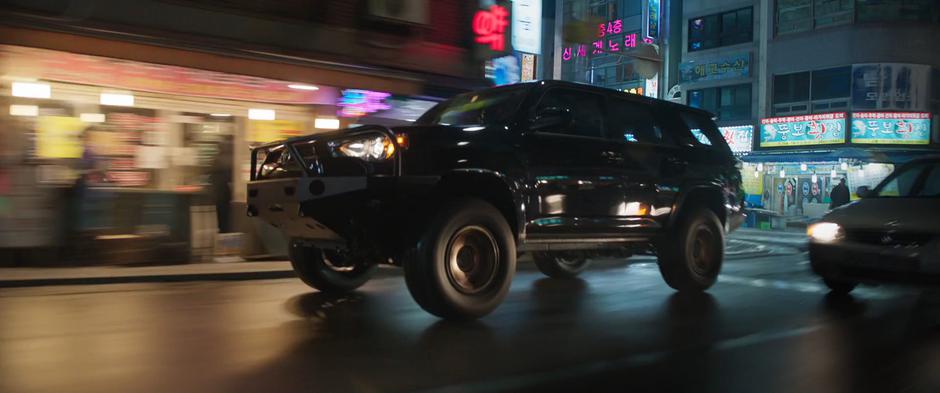 Okoye & Nakia's car follows closely behind one of the SUVs.