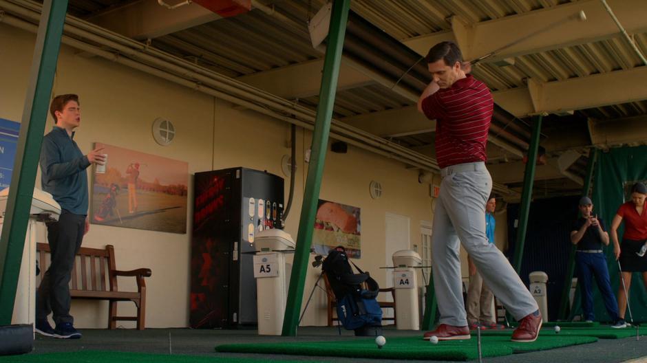 Troy Dickerson talks while his father swings at a ball.