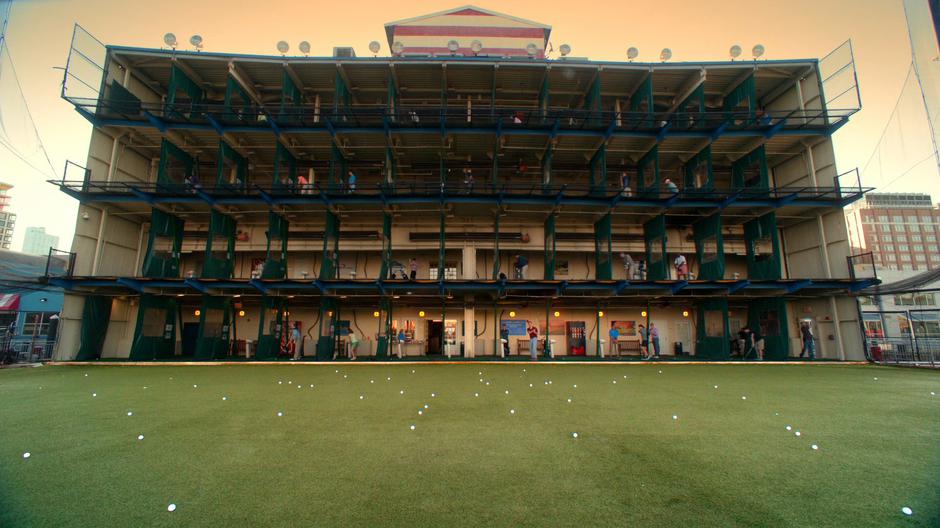 Golfers hit balls out from the multi-story driving range.