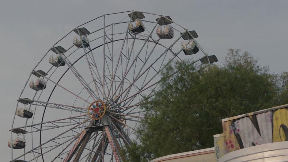 A ferris wheel sits abandoned over the park.