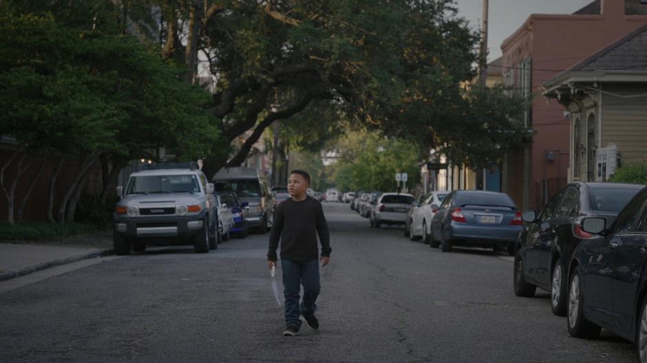 Young Tyrone walks down the middle of the street holding Tandy's lost ballet shoe.