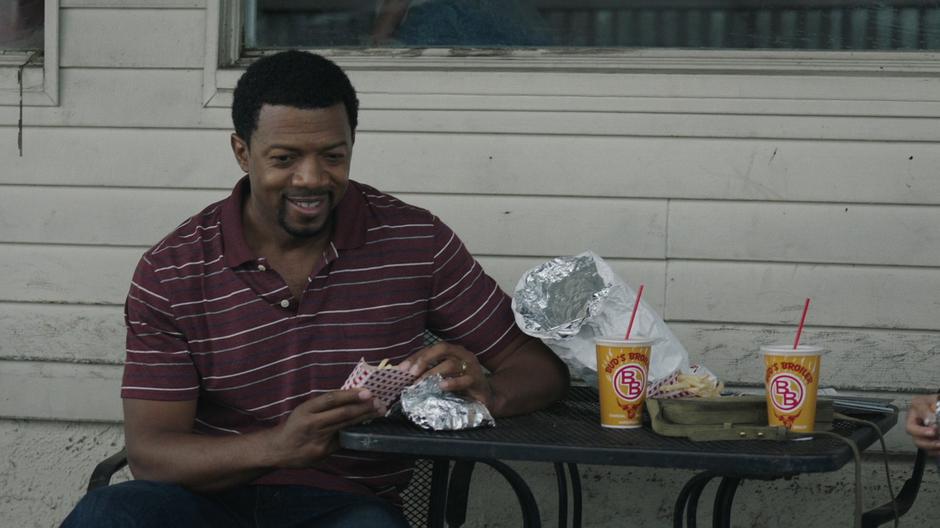 Otis watches his sons talk while opening up their meal.